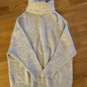  Ny Ljusgrå polotröja från Dilvin Knit - Supermjuk och oversized ljusgrå polotröja från Dilvin Knit. Tröjan är ribbstickad med hög polokrage och långa ärmar, perfekt för lager på lager. Skön och stilren att bära till jeans