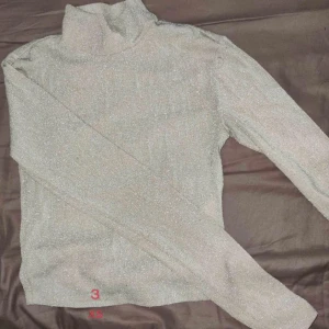 Glittrig beige polotröja XS långärmad - Snygg glittrig polotröja i beige med lång ärm och hög krage. funkar bra nu till jul och nyår och andra högtider✨
