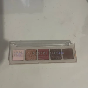 Desert Bloom ögonskuggspalett MUA - Palett med fem ögonskuggor i nyanser av rosa, koppar, vinröd, lila och brun. Kommer i en smidig plastförpackning med genomskinligt lock. Perfekt för att skapa både matta och skimrande looks.
