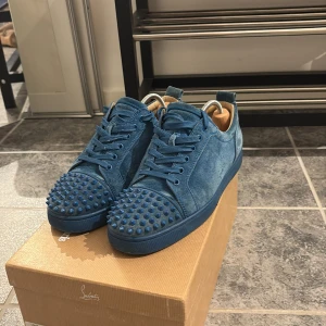 Blå mocka sneakers från Louboutin - Säljer ett par unika blå sneakers från Louboutin i mjuk mocka med matchande blå snörning. Skorna har rund tå och är dekorerade med coola blå nitar framtill. Skriv om ni vill ha fler bilder eller frågor