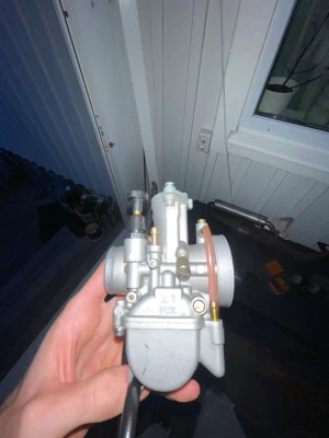 Förgasare 21mm PWK till moped - Säljer en grå förgasare av modell PWK 21mm, perfekt för dig som vill trimma din moped eller scooter. Tillverkad i metall med detaljer i mässing och plast. Passar de flesta mopeder och ger bättre prestanda och respons.