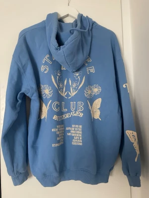 Hoodie bershka  - Blå hoodie med huva och tryck. Stl xs men oversized passform så skulle mer säga s/m. Perfekt för dig som gillar unik streetwear och coola prints.