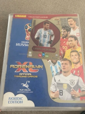 Panini VM 2018 samlaralbum + kort - Säljer ett Panini Collector's Album från fotbolls-VM 2018 i Ryssland, Nordic Edition, med officiella Adrenalyn XL trading cards. Albumet innehåller flera samlarkort med internationella fotbollsspelare, inklusive en Limited Edition Messi-kort. Perfekt för samlare!