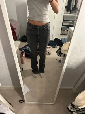 Grå bootcut jeans med låg midja - Säljer ett par gråa bootcut jeans från Junkyard med låg midja och klassiska fem fickor. Jeansen har en snygg tvätt och raka ben som går ut lite nedtill. Perfekta till en avslappnad stil och passar till det mesta. Materialet är troligtvis bomull med stretch för extra komfort.