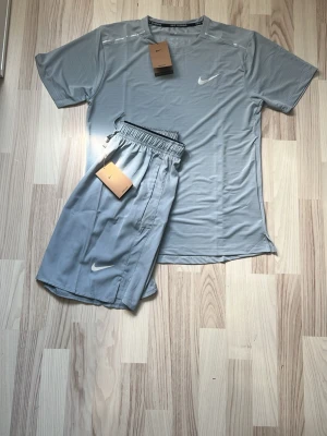 Grått Nike Miller set  - Hej, jag säljer nu ett snyggt grått träningsset från Nike med t-shirt och shorts.  Såklart är det helt nytt med inga defekter. Hör av er om frågor och prisfunderingar!😀