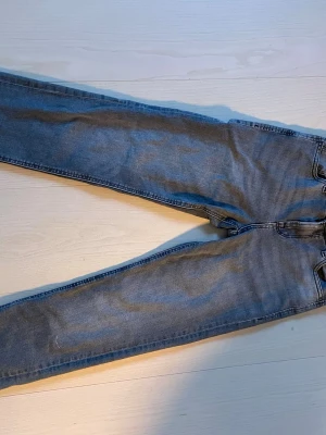 Blå raka jeans med fem fickor - Säljer ett par klassiska blå jeans med rak passform och fem fickor. Jeansen har normal midja och är gjorda i denim. Perfekta till vardagslooken och passar till det mesta i garderoben.