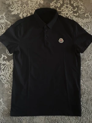 Moncler pike - Fin stilren Moncler pikétröja mörkblå, nyskick testad bara. Perfekt med shorts eller fin byxa för en stilren o clean look, pris kan diskuteras vid snabb affär.