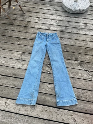 Ljusblå utsvängda jeans - Såå snygga utsvängda jeans med fickor fram från Wrangler! Lite slitna i bensluten, (se bild nr 2), annars i utmärkt skick! Hör av dig om du har några funderingar🥰