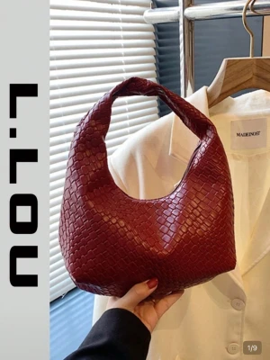 Vinröd axelväska i flätad look - Trendig vinröd handväska med flätad struktur och rundad form. Väskan har ett kort handtag och är tillverkad i konstläder. Perfekt storlek för det viktigaste och ger en cool vibe till din outfit.