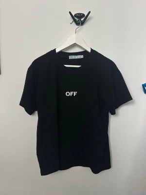 Svart t-shirt med OFF-tryck - Säljer en svart t-shirt med vitt OFF-tryck på bröstet. Klassisk rund halsringning och korta ärmar. Tillverkad i mjuk bomull som känns skön mot huden. Perfekt för dig som gillar enkel och stilren design.