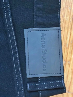 Svarta wide leg jeans Acne Studios - Säljer ett par svarta wide leg jeans från Acne Studios. Jeansen har hög midja, raka och vida ben samt klassiska fem fickor. Materialet är kraftig denim med tydliga sömmar. Perfekta för en trendig och avslappnad look. är ej från acne studios