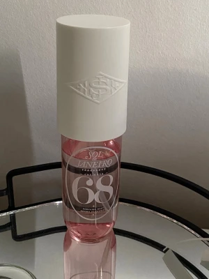 Sol de Janeiro Cheirosa 68 Parfymmist - Fräsch parfymmist från Sol de Janeiro i en rosa genomskinlig flaska med vit spraykork och lock. Flaskan har en modern design med tydlig märkning '68' på framsidan. Perfekt för dig som gillar lätta och blommiga dofter.
