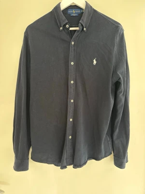 Mörkblå Ralph Lauren skjorta - Hej! Säljer nu denna sjukt eftertraktande mörkblå Ralph Lauren skjorta i det uppskattade ”featerweight mesh” materialet. Funkar att ha både med eller utan T-shirt och kan användas i formella eller mer avslappnade miljöer tack vare dess stilrena look. | Storlek: L | Skick: 8,5/10 | Meddela gärna vid eventuella frågor! Mvh ResellGarms