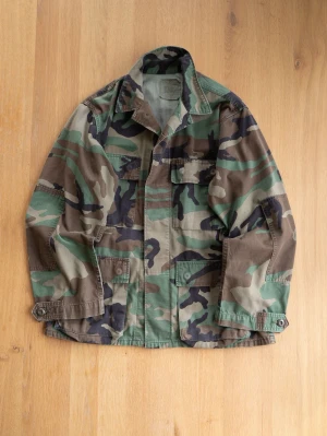 Army Jacket, size M - Säljer en overshirt i klassiskt militärinspirerat camomönster med gröna, bruna och svarta toner. Skjortan har fyra fickor framtill, knappar och krage. Tillverkad i slitstark bomull, perfekt för lager på lager och streetwear.