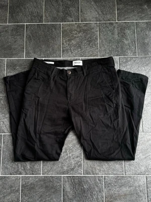 Jack & Jones Chinos - Tja! Säljer nu mina svarta chinos från Jack & Jones i storleken w32/30! Skicket är mycket bra, och plagget är enbart använt någon enstaka gång! Nypris ligger på ca 500kr! Vid frågor eller funderingar är det bara att höra av sig!