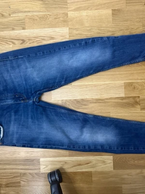 Mörkblå slim fit Levi’s jeans - Snygga mörkblå slim fit jeans med lätt slitning på låren och klassiska bakfickor. Jeansen har normal midja och smal passform hela vägen ner. Perfekta till vardagsstilen och funkar året runt.