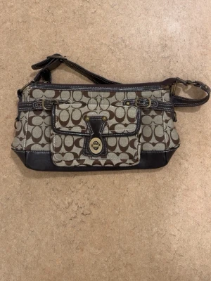 Vintage läderväska – possibly Coach style  - Vintage Coach-inspirerad väska med flera detaljer som stämmer överens med äldre Coach-modeller. Jag har granskat bland annat materialet, sömmarna, loggan och detaljerna på väskan, och den verkar överensstämma med vintage Coach-design. Jag har dock inget kvitto eller originalbevis kvar, så jag kan inte garantera äktheten till 100 %. Säljs därför med ärlig beskrivning. En väldigt fin och tidlös vintageväska för dig som gillar klassisk stil 🤎