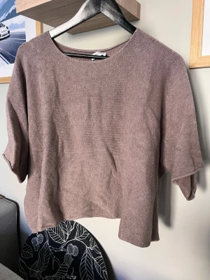 Beige loose topp från Mix by Heart - En enkel och stilren beige topp från Mix by Heart. Modellen är loose fit med korta ärmar och rund halsringning. Materialet känns mjukt och har en lätt struktur, perfekt för en avslappnad look.