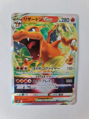 Pokémon Charizard VSTAR japanskt kort - Säljer ett japanskt Pokémon Charizard VSTAR samlarkort med holografisk yta. Kortet har färgstark design med Charizard i orange och gult, och text på japanska. Perfekt för dig som gillar Pokémon och vill utöka din samling.