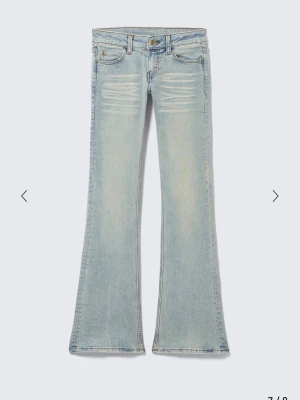 Ljusblå bootcut jeans - Säljer ett par ljusblå bootcut jeans med snygga slitningar framtill och klassiska fem fickor. Jeansen har utsvängda ben och en cool vintagekänsla. Perfekta för dig som gillar retrostil och vill sticka ut lite extra.