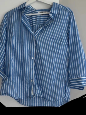 Blåvit randig blus Hampton Republic - Säljer en blå och vit randig blus från Hampton Republic. Den har klassisk krage, knappar framtill och långa ärmar med manschett. Tillverkad i ett lätt och svalt material, den är lite mindre i storlek och passar mig som har XS och S