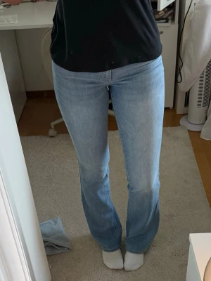 Ljusblå bootcut jeans från ONLY - Säljer ett par ljusblå jeans från ONLY med klassisk femficksmodell och bootcut-ben. Jeansen har normalhög midja och är tillverkade i mjuk denim med lite stretch för extra komfort. Perfekta för en avslappnad och trendig look. Jag är ca 175 och de är perfekt längd!