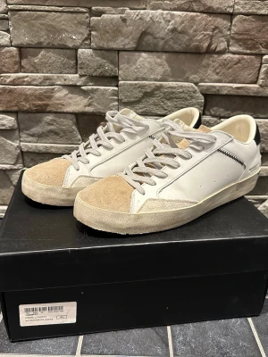 Vita och beige sneakers med mockadetaljer - Crimelondon skor i storlek 41. Cirka 8/10 skick.  Är en perfekt sko till sommaren. Tveka inte att höra av er vid minsta fundering.