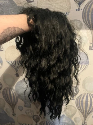 Svart peruk  - Svart vågig peruk. Relativt lätt att kamma. Har en lugg men mer av en curtain bang när man har den på. Oanvänd mer än testad en gång. Wig cap skickas med omställbar inuti. 
