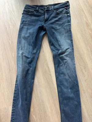 Mörkblå slim fit jeans från Replay - Snygga mörkblå slim fit jeans från Replay med klassisk femficksmodell och diskret slitning på låren. Jeansen har normal midja och raka ben, perfekta för en avslappnad men stilren look. Tillverkade i mjuk och stretchig denim för extra komfort.