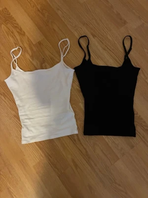 2-pack linnen från Gina Tricot XS - Två stilrena linnen från Gina Tricot i svart och vitt. Båda har smala axelband och figurnära passform. Perfekta att matcha till olika outfits och enkla att bära till vardags. Materialet är mjukt och stretchigt för extra komfort.