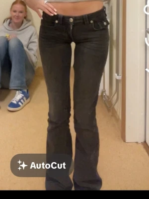 Svarta bootcut jeans med låg midja - Säljer ett par svarta bootcut jeans från true religion med låg midja och klassisk femficksmodell. Jeansen har en tight passform upptill och utsvängda ben. Perfekta för dig som gillar en retro och trendig look. Materialet är denim med stretch för extra komfort. Storlek 24