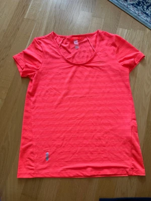 NY Neonrosa tränings-tshirt från Only Play - Säljer en neonrosa tränings-tshirt från Only Play. T-shirten har rund halsringning, korta ärmar och diskreta horisontella ränder i materialet. ALDRIG ANVÄND!