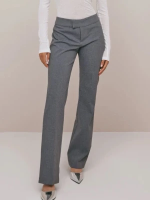 Grå kostymbyxa med raka ben - Snygga grå kostymbyxor med hög midja och raka ben. Byxorna har en klassisk passform och stängs med dold hake och dragkedja framtill. Perfekta för en clean och stilren look. Noppriga