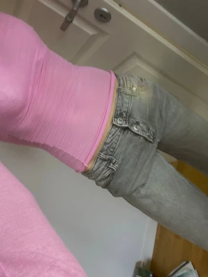 Grå raka jeans med låg midja - Säljer ett par grå jeans med låg midja och raka ben. Jeansen har tre knappar framtill, annars klassiska jeans från Gina Tricot. Materialet är denim och färgen är ljusgrå med lite slitningar vid fickorna. 🥰