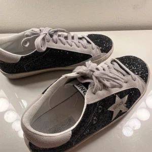 Golden Goose liknande sneakers  - Snygga svarta sneakers med glittrig yta och vita detaljer från GONR. Skorna har snörning och en stjärndetalj på sidan. Perfekta för att ge din outfit lite extra bling. Aldrig använda då dom är för stora för mig, skriv vid frågor eller liknande🩷🥰