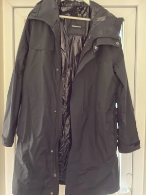 Svart lång regnjacka med huva - Peak Performance vinterjacka – storlek M  Säljer en stilren svart vinterjacka från Peak Performance i storlek M.  🖤 Svart 🧥 Varm och fodrad ☔ Perfekt för höst/vinter ✨ Mycket fint skick 📏 Storlek M  Jackan är sparsamt använd och har inga synliga större skador eller defekter.  