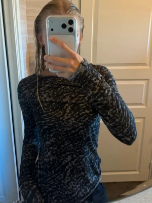 Mörk långärmad topp med zebramönster - Säljer en mörkgrå långärmad topp med zebramönster. Toppen har en normal passform och är tillverkad i ett mjukt, stretchigt material som känns skönt mot huden. Perfekt för dig som gillar djurmönstrat och vill ha en unik look.
