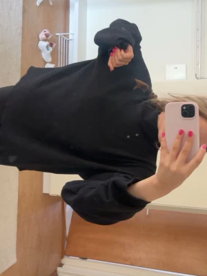  svart  tjocktröja  - Säljer en oversized svart hoodie med klassisk design. Hoodien har långa ärmar, ribbade muddar och en rymlig passform. Perfekt för dig som gillar en enkel och stilren look. Materialet känns mjukt och bekvämt mot huden.