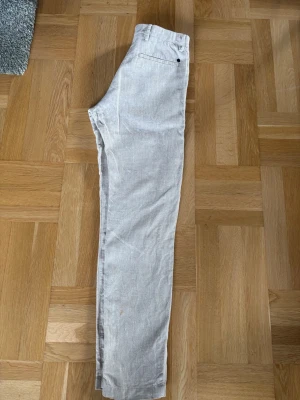 Beige linnebyxor från NN07 - Snygga beige linnebyxor från NN07 med raka ben och klassisk passform. Byxorna har bälteshällor, knappgylf och sidofickor. Tillverkade i ett luftigt linnetyg som passar perfekt för varma dagar.