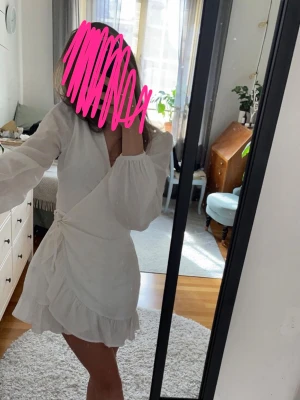 Vit omlottklänning med volang - Superfin vit linne klänning. En omlottklänning med långa ärmar och volangkant nertill. Klänningen har knyt i midjan och v-ringad hals. Från BikBok. Kontakta om du har några frågor💕