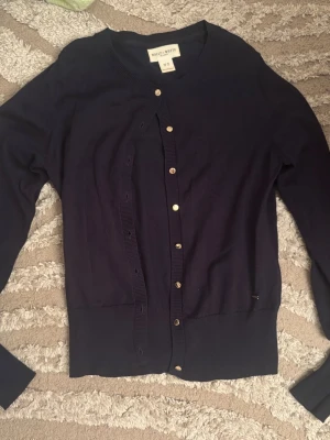 Mörkblå kofta från Holly & Whyte XS - Mörkblå kofta från Holly & Whyte by Lindex med rund halsringning och knappar framtill. Långärmad modell i mjukt, tunt material med ribbade muddar vid ärmslut och nederkant. Perfekt att slänga över en topp eller klänning. Knappt använd.