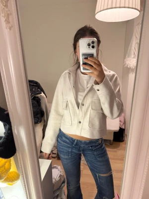 Vit croppad jeansjacka med fickor - Är ganska nopprig🩷Snygg vit croppad jeansjacka med två stora bröstfickor och knappar framtill. Jackan har en avslappnad passform och klassisk krage, perfekt att styla till jeans eller kjol för en trendig look.