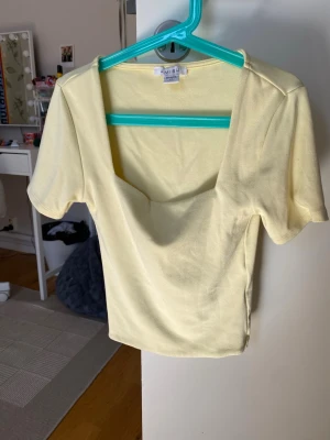 Ljusgul topp från Amisu - Snygg ljusgul topp från Amisu med fyrkantig urringning och korta ärmar. Tillverkad i mjukt bomullsmaterial och har en slim passform som sitter snyggt på kroppen. Perfekt att styla med jeans eller kjol för en fräsch look.