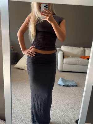 Mörkgrå set med topp och lång kjol - Säljer detta set från Gina tricot. Mjuk och stretchig passform. Använd fåtal gånger. Obs säljer hela settet alltså inte separata delar 