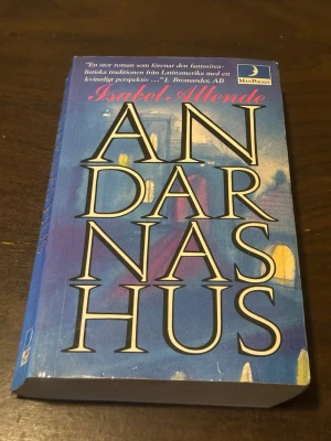 Andarnas hus av Isabel Allende - En episk roman av Isabel Allende som blandar magisk realism och släktkrönika. Boken har ett blått omslag med stora vita bokstäver och ges ut av ManPocket. Perfekt för dig som gillar latinamerikansk litteratur och starka berättelser.