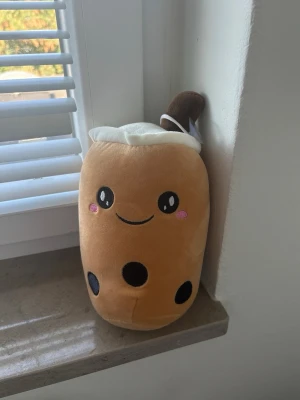 Söt boba plushie mjukisdjur - Supergulligt mjukisdjur som ser ut som en boba-te med glad ansikte, bruna bollar och ett sugrör på toppen. Färgerna är beige, brun och vit med rosa kinder. Perfekt som dekoration eller kramkompis. Tillverkad i mjukt plyschmaterial. 🫶🏼🤗