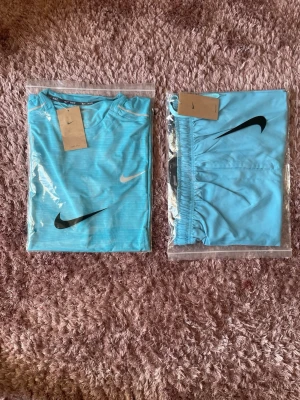 Nike ljusblått träningsset - Storlek XL men passar också L.                          Säljer ett ljusblått träningsset från Nike med t-shirt och shorts. Båda plaggen har Nike-loggan tryckt framtill. Materialet är lätt och andas, perfekt för träning eller sportaktiviteter. Snygg och sportig design med elastisk midja på shortsen.