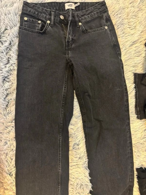Svarta low rider jeans från 157 - Snygga svarta low rider jeans från 157 med klassisk femficksmodell och raka ben. Jeansen har silverfärgade nitar och dragkedja. Perfekta för en avslappnad och trendig look. Materialet är denim i bomull.