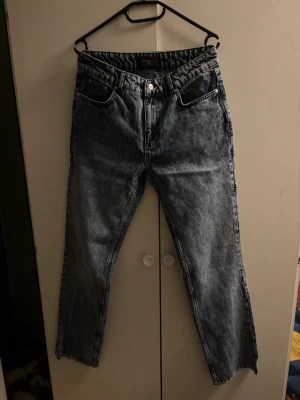 Baggy ljusblå jeans med raka ben - Säljer ett par baggy ljusblå jeans med raka ben och stentvättad finish. Jeansen har klassiska fem fickor, extra fickdetaljer på ena benet och broderade bakfickor. Perfekta för en avslappnad streetstil.