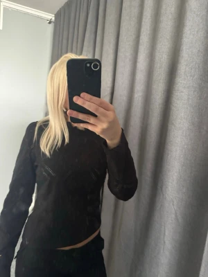 Svart långärmad topp från NAF NAF - Säljer en svart långärmad topp från NAF NAF. Toppen har en hög hals och är tillverkad i ett tunt, lätt material med diskreta håldetaljer som ger en cool touch. Perfekt att styla med jeans eller kjol för en trendig look.